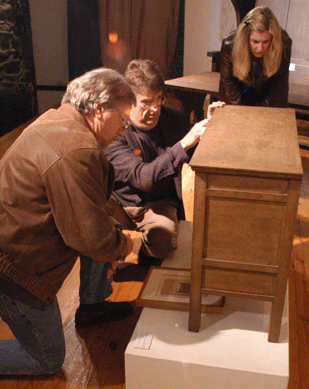 Auctioneer James Bakker looks over a chiffonier