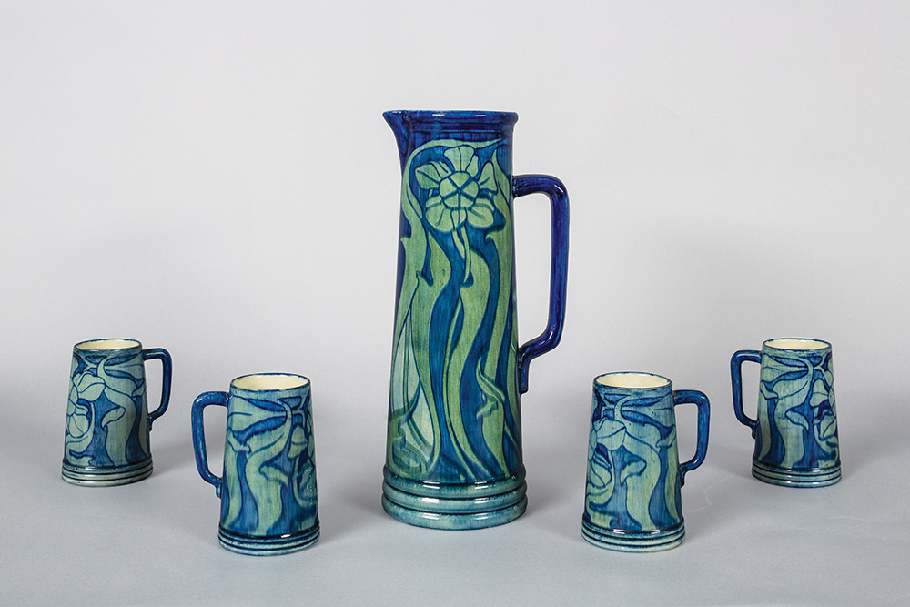 Fig. 5 - Pitcher and four tankards, c. 1901. Marie de Hoa Le Blanc, American, 1874-1954, designer and decorator. Joseph Fortune Meyer, American, 1848-1931, maker. Newcomb Pottery, New Orleans, LA, manufacturer. Glazed earthenware. Pitcher: 14 ½ inches high; tankards 5 ¼ inches high. TRRF Collection.