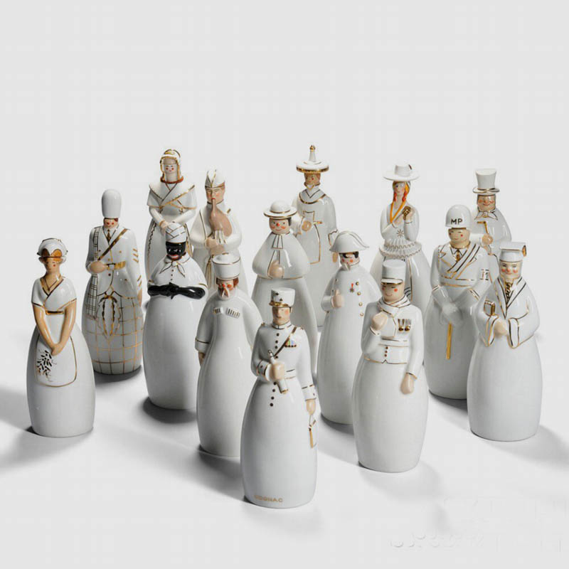 Fifteen Robj Liqueur Decanters, Glazed Ceramic, France, 20th Century, The anthropomorphic containers in white glaze with gold highlights represent: a kilted Scotsman, French soldier, African woman, military policeman, Russian peasant, bagpiper, priest, gentleman in a top hat, general with field telescope, Napoleon Bonaparte, professor, and four women in traditional folk dress representing Champagne, Brittany, Bresse, and Mont Cenis, marked with various Robj stamps, some also marked Limoges, approx. ht. 11 in.